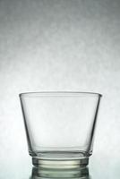 una toma vertical de un vaso vacío sobre un fondo gris foto