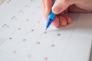 mano de mujer con bolígrafo escribiendo en la fecha del calendario concepto de reunión de cita de planificación empresarial foto