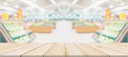 Wood table top with supermarket grocery store blurred defocused background with bokeh light for product display photo