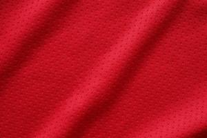 Red sports clothing fabric football shirt jersey texture close up photo