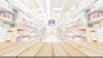 mesa de madera con fondo borroso interior del pasillo de la tienda de comestibles del supermercado con luz bokeh para la exhibición del producto foto