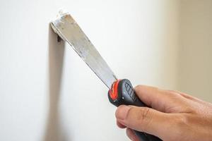 Man repairing crack white wall with spatula photo