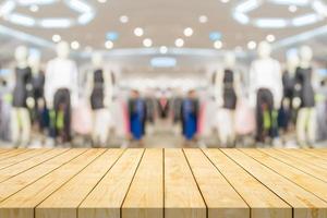 Empty wood table top with blur clothing boutique display interior shopping mall background photo