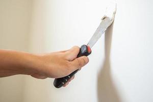 Man repairing crack white wall with spatula photo