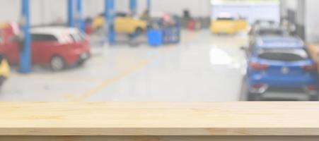 Empty wood table top with car service centre auto repair workshop blurred background photo