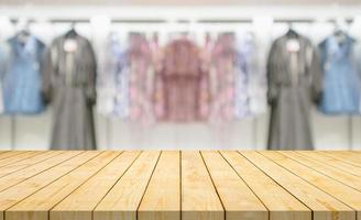 Empty wood table top with blur clothing boutique display interior shopping mall background photo