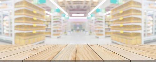 mesa de madera con fondo borroso interior del pasillo de la tienda de comestibles del supermercado con luz bokeh para la exhibición del producto foto