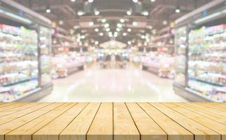 Empty wood table top with supermarket grocery store aisle and shelves blurred background photo