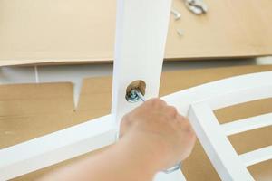 Man assembling white chair furniture at home photo