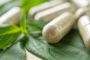 Herbal medicine capsules with Andrographis paniculata leaf on wood table photo