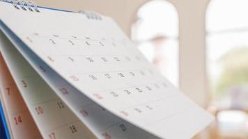 Close up white paper desk calendar with blurred bokeh background appointment and business meeting concept photo