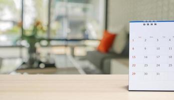 white paper desk calendar on wood table with blurred bokeh background appointment and business meeting concept photo