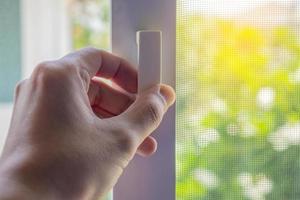 Hand hold mosquito net wire screen handle on house window photo
