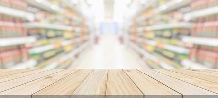 mesa de madera con fondo borroso interior del pasillo de la tienda de comestibles del supermercado con luz bokeh para la exhibición del producto foto