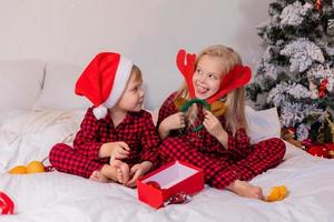 two happy children in pajamas for Christmas are sorting presents and playing with Christmas toys. High quality photo