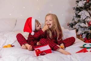 two happy children in pajamas for Christmas are sorting presents and playing with Christmas toys. High quality photo