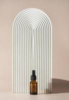 A face or hair serum or essential oil in a brown dropper bottle lstanding near the white ceramic tray photo