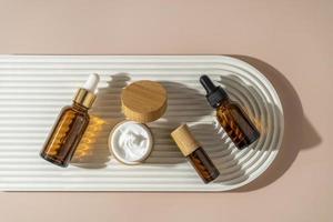 A face or hair serum or essential oil in a brown dropper bottle lying on a white ceramic plate. Product marketing cosmetics mockup photo
