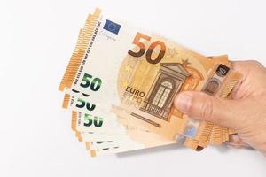 Hand holding a group of 50 euro banknotes on white background. Copy space photo