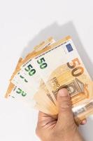 Hand holding a group of 50 euro banknotes on white background. Copy space photo