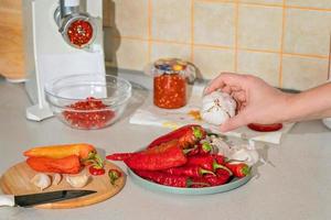 cooking adjika from hot pepper and garlic ground in a meat grinder. preparations for the winter. folk remedy for flu and colds photo