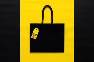 Black shopping bag with yellow price tag on yellow and black background for Black Friday shopping sale concept. photo