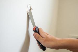 Man repairing crack white wall with spatula photo