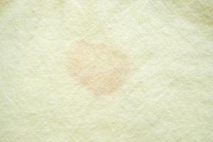 dirty color stain on yellow fabric texture background photo