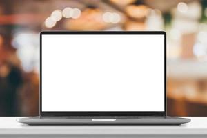 Laptop with blank screen on marble table with cafe coffee shop blur background photo