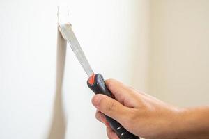 Man repairing crack white wall with spatula photo