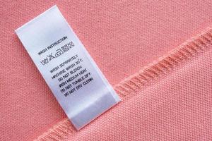 White laundry care washing instructions clothes label on pink cotton shirt photo