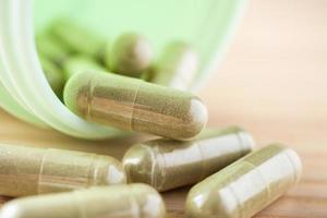 Herbal medicine capsules with bottle on wood table photo