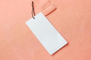 Blank white clothes tag label on pink fabric texture background photo