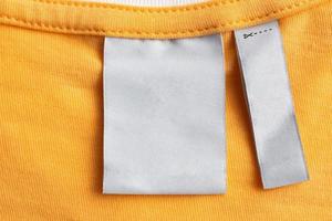 Blank white laundry care clothes label on yellow fabric texture background photo