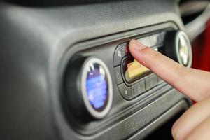 Woman hand turn on car air conditioning system photo