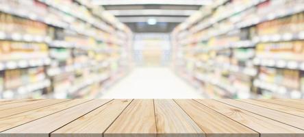 Wood table top with supermarket grocery store aisle interior blurred background with bokeh light for product display photo