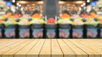 Empty wood table top with blur fruits in basket supermarket grocery store background photo