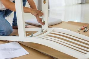 Man assembling white chair furniture at home photo