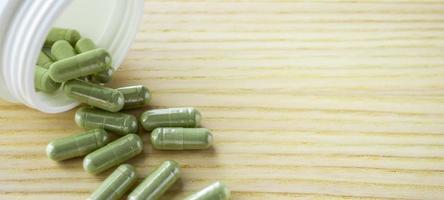 Herbal medicine capsules with bottle on wood table photo