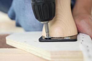 man assembling sofa furniture at home using cordless screwdriver photo
