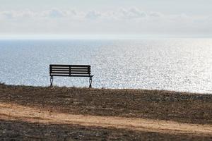 Empty bench on cliff before sea background, peaceful and quiet place for thinking alone photo