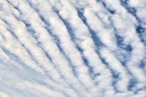 Beautiful blue sky with unusual white Altocumulus undulatus clouds, extraordinary cloud formation photo