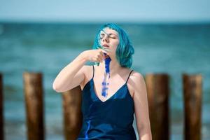 Artistic blue-haired woman performance artist in dress smeared with blue gouache paints on her body photo
