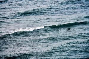 Deep blue sea waters splashing with foamy waves, dark blue wavy ocean water surface, copy space photo