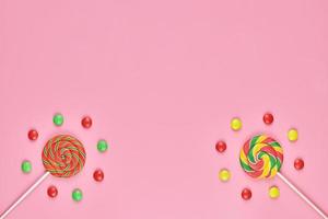 piruletas dulces y caramelos sobre fondo rosa foto
