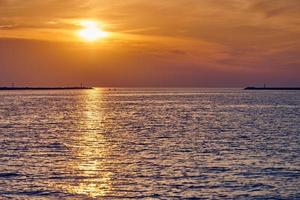 Calm sea with sunset sky, beautiful scenic view, amazing dramatic rising sun reflected in water photo