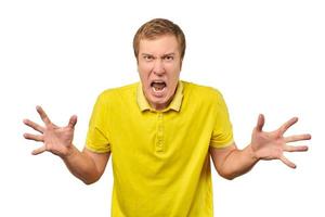 Angry young man in yellow T-shirt spread his hands and yelling isolated on white background photo