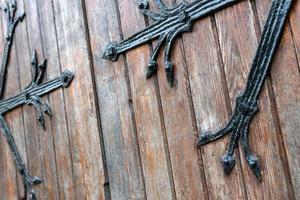 patrón de puerta forjada, decorativa. antigua entrada vintage, enorme puerta de madera pesada de iglesia o catedral. foto