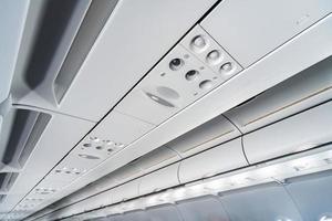 Airplane air conditioning control panel over seats. Stuffy air in aircraft cabin with people. New low-cost airline. photo