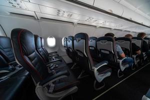 Airplane cabin seats with passengers. Economy class of new cheapest low-cost airlines without delay or cancellation of flight. Travel trip to another country. photo